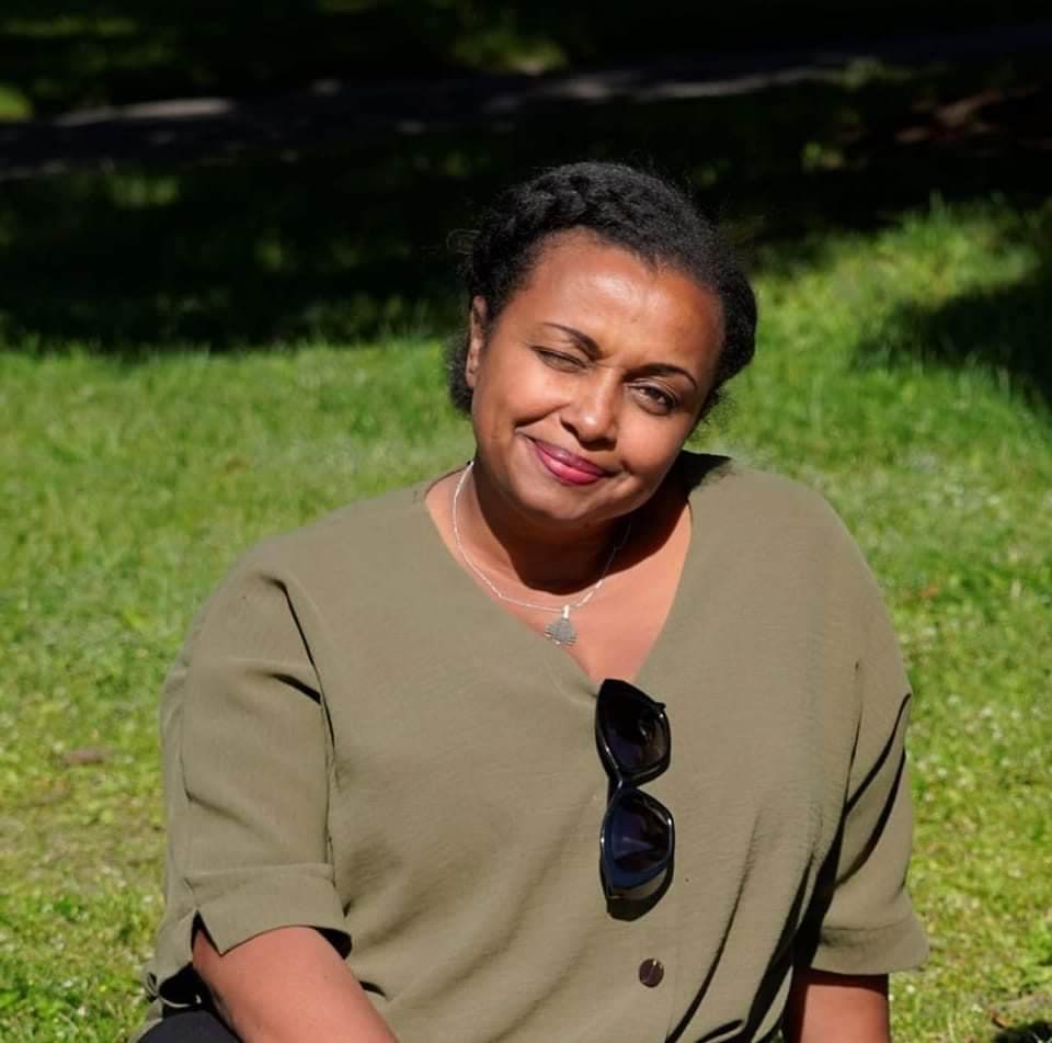 Nainen istuu nurmikolla